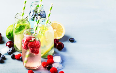 Summer drinks set. Berry, fruit and citrus non-alcoholic refreshing ice cold beverages and cocktails in glass bottles on blue background