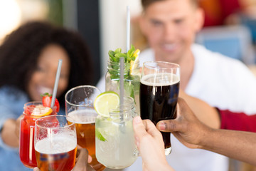 leisure, food and people concept - group of happy international friends clinking glasses at bar or restaurant