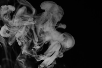 Fototapeta premium White smoke on a black background. Texture of smoke. Clubs of white smoke on a dark background for an overlay