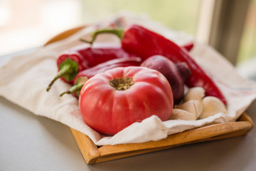 Linen napkin with red chili peppers and garlic cloves with tomato and onion on wooden tray