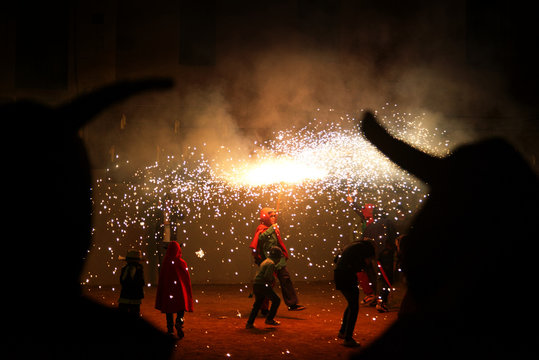 Ball de Diables street performance in Catalonia. Happy people dancing with some fireworks in a traditional street celebration. Empty copy space for Editor's text.