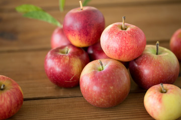 fruits, food and harvest concept - ripe red apples on wooden table