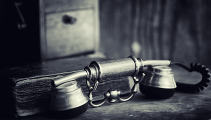 Old telephone and retro book on the desk. The phone of the past on an old wooden countertop....