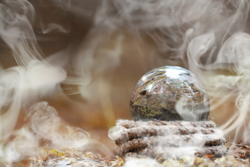 A crystal ball in the smoke. A magical accessory in the woods on the stump. Ritual ball of witches and sorcerers on an old rotten stump covered with moss.