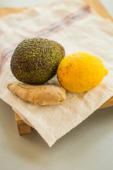 Avocado with lemon and ginger root on wooden cutting board , close-up