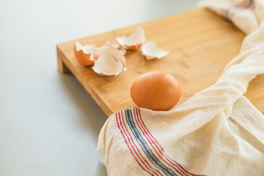 Egg with broken shell on wooden cutting board, close-up