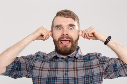 Funny crazy playful handsome man in plaid shirt making silly monkey face bulging ears showing tongue. Guy having fun, teasing play tricks foolish mood pose on white studio background