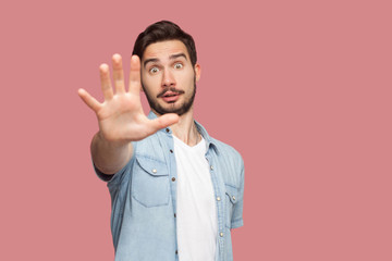 Stop it. Portrait of shocked handsome bearded young man in blue casual style shirt standing with...