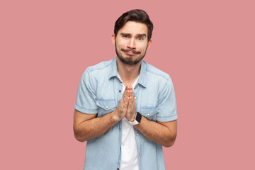 Please help me, or forgive. Portrait of sad hopeful handsome bearded young man in blue casual style...