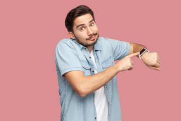 Portrait of sad handsome bearded young man in blue casual style shirt standing pointing and showing...