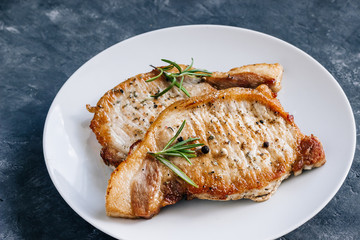 Roasted pork steaks in a plate with Rosemary.