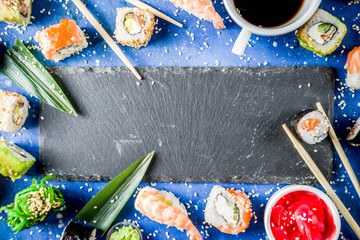 Assorted sushi set on stone or concrete background.  Japanese classic sushi, sushi nigiri. rolls, soy sauce, ginger, chopsticks. Top view. copy space