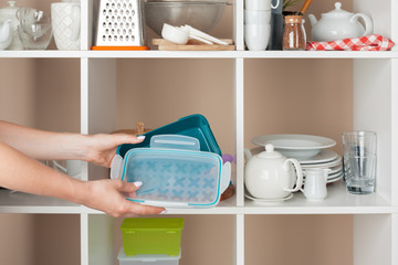 Woman hand taking dishware pieces from shelf in kitchen