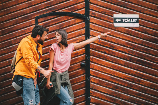 Young couple with beer in hand is searching for a public toilet on the street
