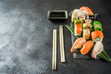 Assorted sushi set on stone or concrete background.  Japanese classic sushi, sushi nigiri. rolls, soy sauce, ginger, chopsticks. Top view. copy space