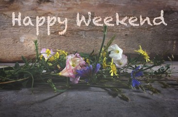 Happy weekend text with wild flower and wooden background