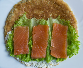 Sandwich of oatmeal, red fish salmon, cucumber, cheese, lettuce