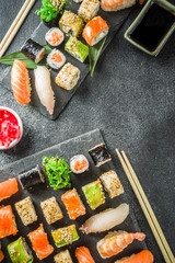 Assorted sushi set on stone or concrete background.  Japanese classic sushi, sushi nigiri. rolls, soy sauce, ginger, chopsticks. Top view. copy space
