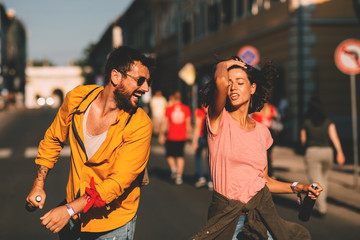 Young couple dancing on the street and holding two bottles of beer
