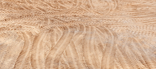 Many traces of the tread of cars in the sand. The tracks cross each other in different directions.