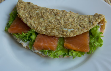 Sandwich of oatmeal, red fish salmon, cucumber, cheese, lettuce