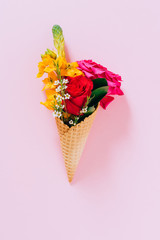 Flat lay Ice Cream Cones with colorful bouquet on pink background, copy space