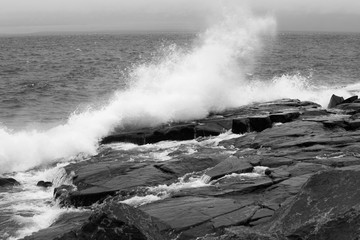 Waves crashing on the rocky shore in black and white