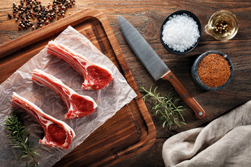 Raw lamb rib chops on white cooking paper and wooden cutting table
