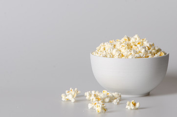 popcorn in a bowl isolated on white with few popcorn beside bowl
