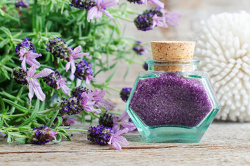 Vintage glass bottle with aroma lavender bath salt (exfoliation scrub, foot soak). Topped lavender flowers close up. Natural skin are. DIY beauty treatments and spa concept. Copy space.