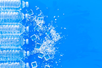 Plastic bottles with pure water and ice on blue background top view space for text