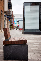 Modern brown wooden bench and empty billboard on the sidewalk