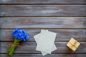 Summer flowers pattern with bouquet of blue cornflowers, envelopes and gift in box on wooden background top view mock up