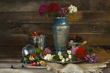 Garden berries in iron buckets and flowers in a jug.