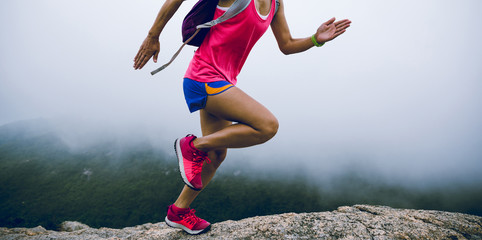 Woman ultra marathon runner running up to the foggy mountain top