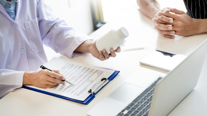 health care concept, doctor give a medicine bottle of drugs pills and explain the direction to use...