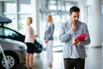 Successful businessman in a car dealership - sale of vehicles to customers