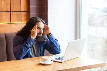 Portrait of thoughtful handsome young adult man freelancer in casual style sitting in cafe with...