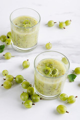 Gooseberries, blended smoothie, glasses full of healthy drink on the white table