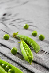 Open pod of peas with green juicy peas on the tablecloth. Close up.