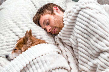 red dog sleeps mask with his owner in the bed. Concept weekend and rest