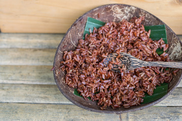 Red steamed rice in the shell on wood table.
