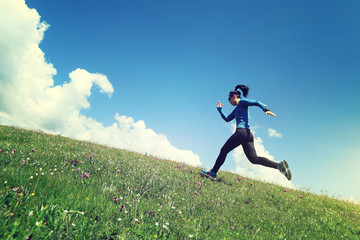 Woman ultramarathon trail runner running up on grassland mountain