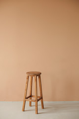 Round wooden stool with beige wall background interior