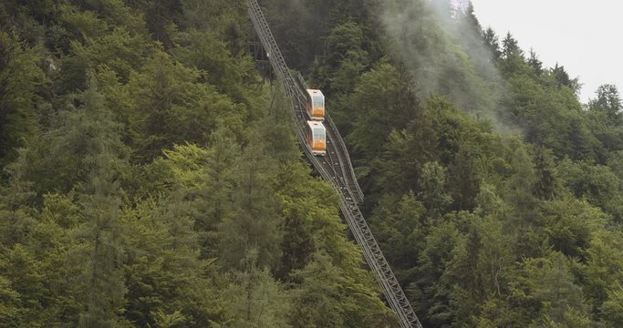 Funicular Railway going up and down between World Heritage Viewpoint to Hallstatt. Clouds moving. Slowmo.