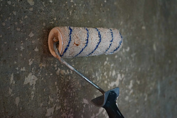 large roller to paint on the background texture of gray concrete wall