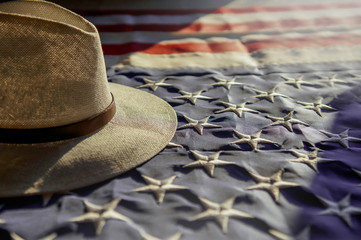 American flag and a hat of cowboy in the light of setting sun