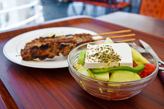 Classic Greek salad and kebabs in the background. Selective focus.
