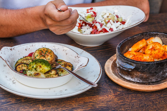 National Montenegrin food. Salty pancakes with meat and cheese in a cast-iron pot, baked vegetables and sopska salata on the table in the restaurant.