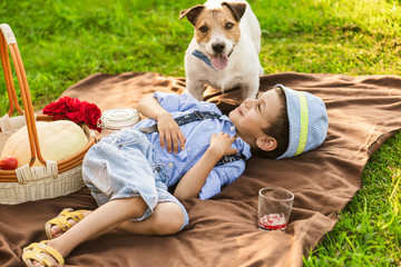 Boy playing with dog at family picnic at green grass lawn